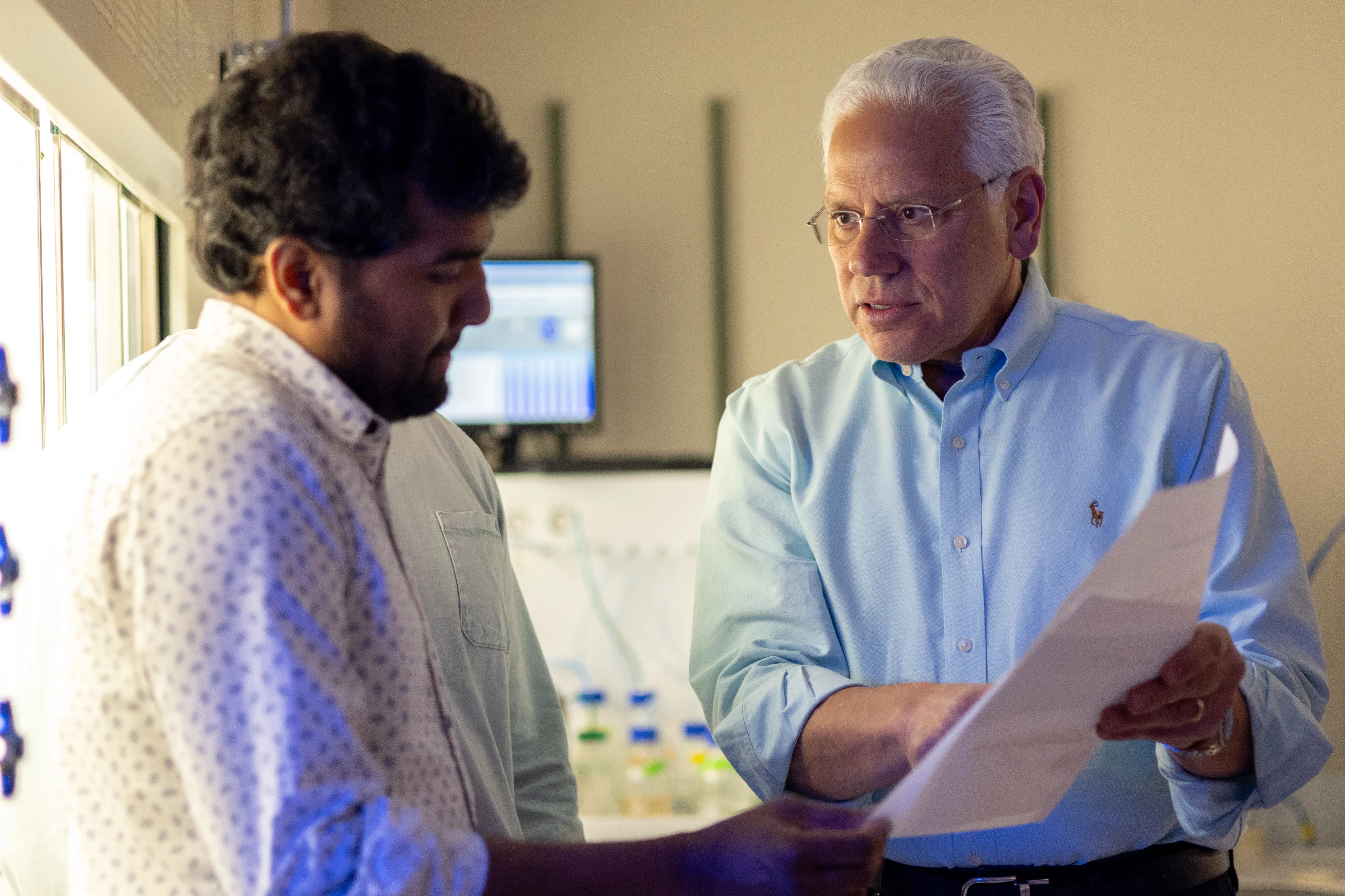 Faculty mentor and fellow reviewing research documents in a laboratory setting