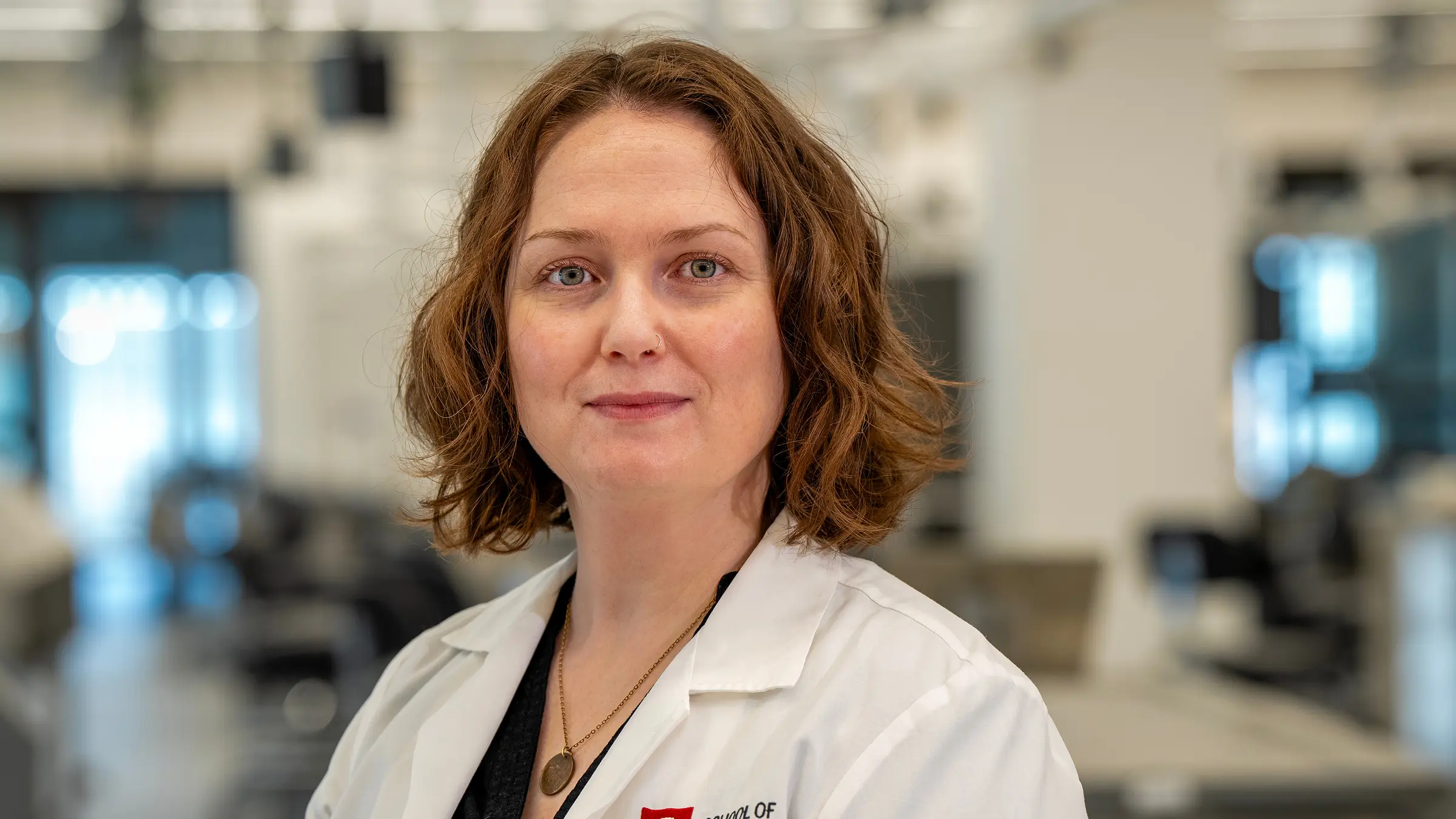 A woman in a lab coat stands in front of the anatomy lab