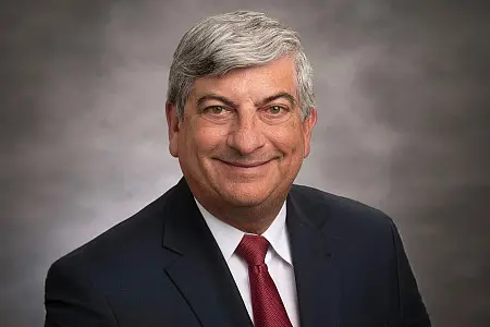 A man in a suit in front of a gray background
