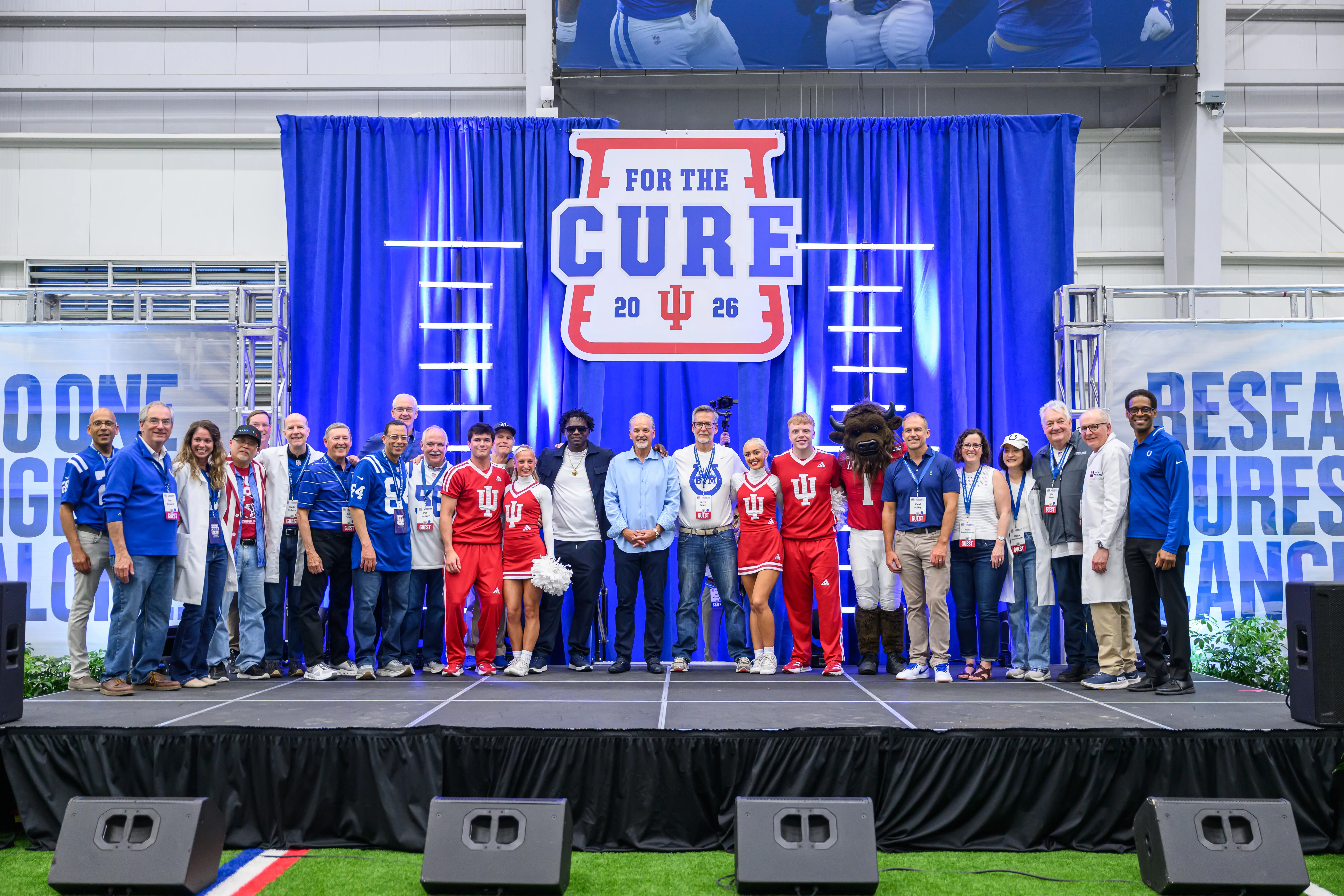 A large group on stage with a blue chuckstrong banner behind them.