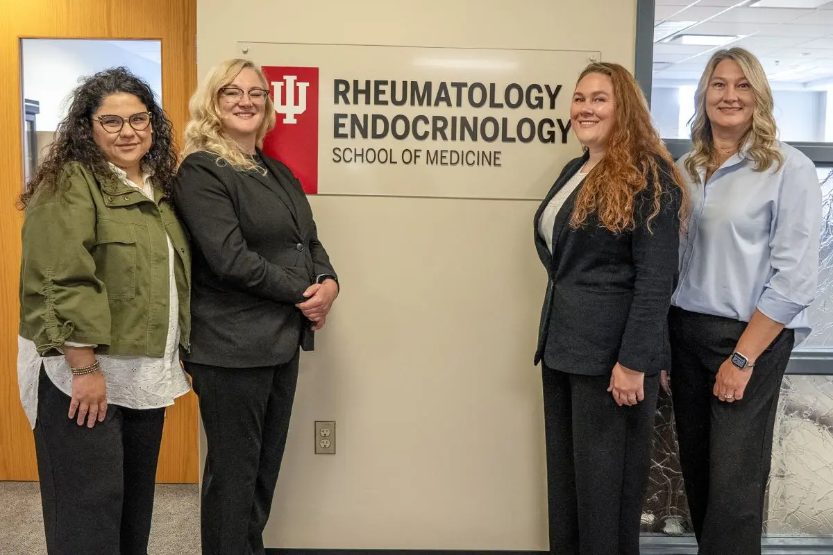 Four smiling staff members stand outside an office suite