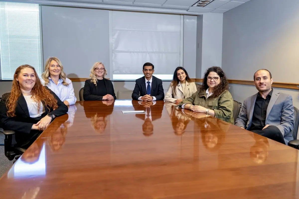 Seven smiling people sit around a conference table.