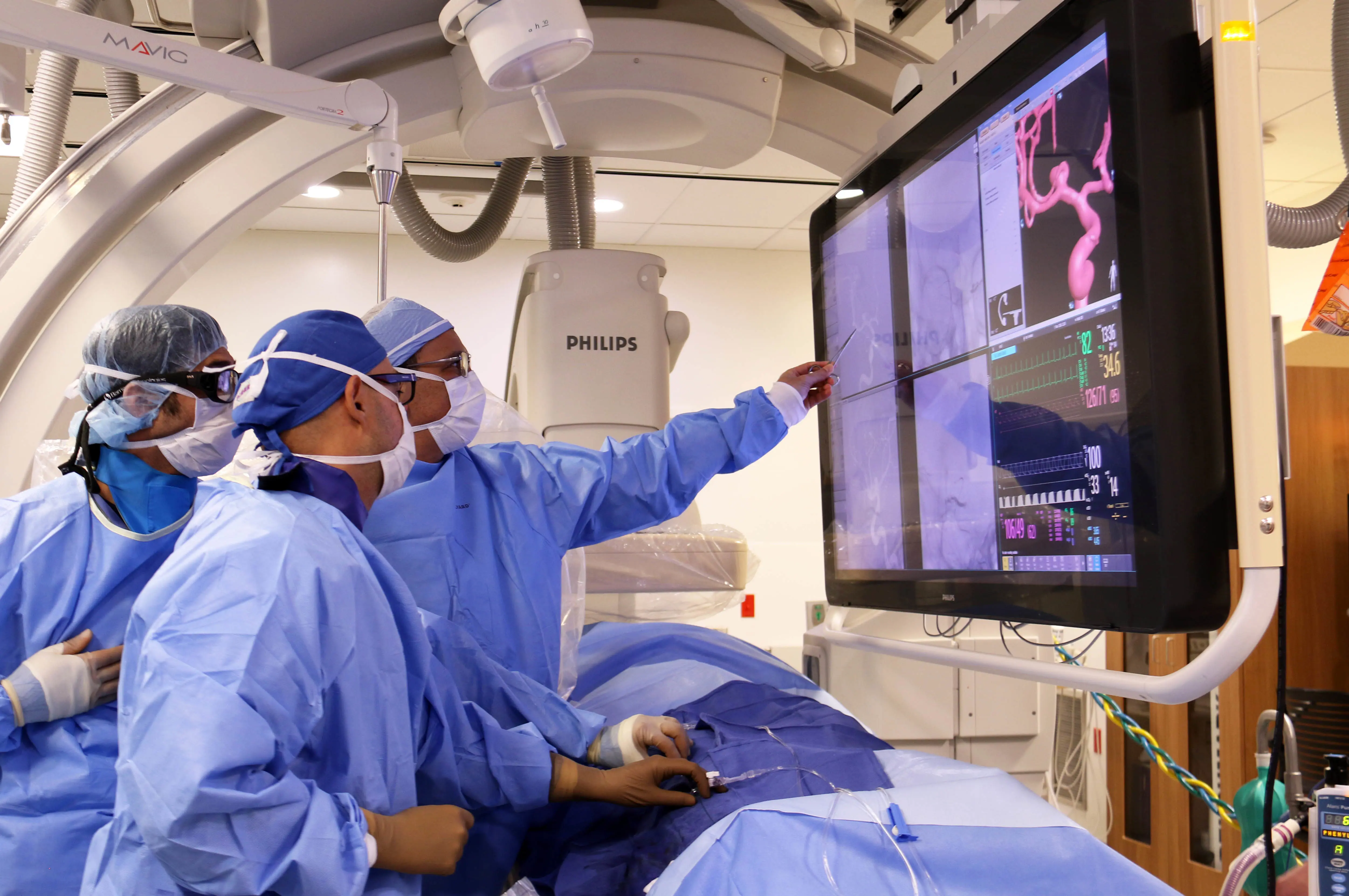 Three interventional radiologists perform a procedure.