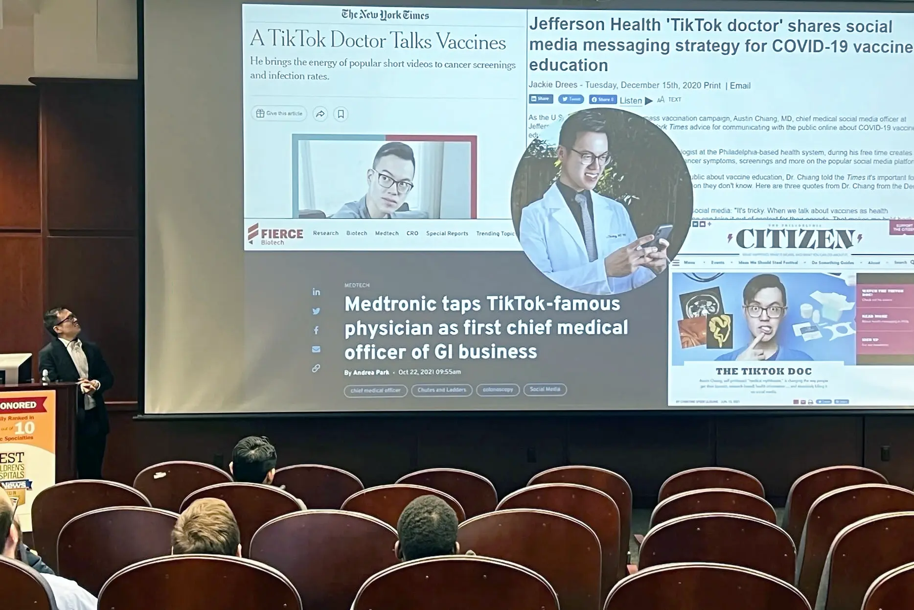 Dr. Austin Chiang speaks in an auditorium beside a slide showing news coverage of a physician's use of TikTok and social media for health education.
