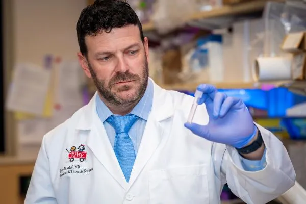 Troy Markel examines a test tube in a laboratory.