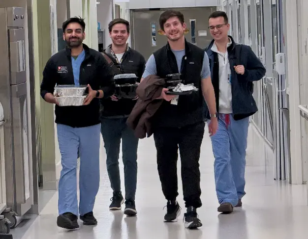 Fellows in scrubs walk down a hospital hallway together.