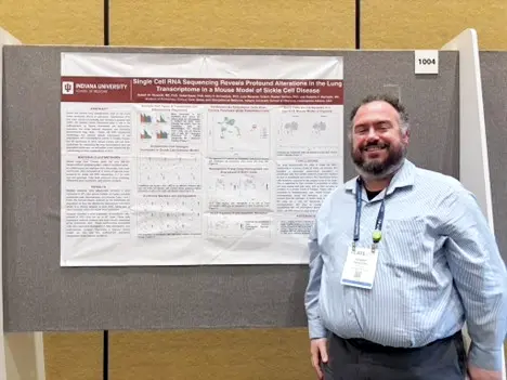 PCCM fellow standing beside a research poster presentation at an academic conference