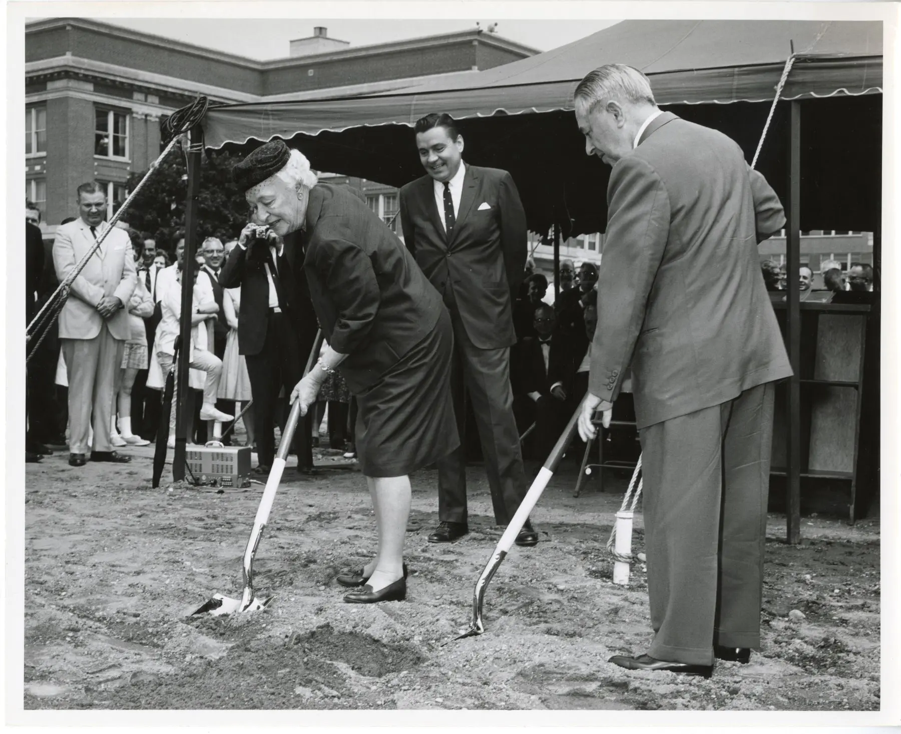 A man and a woman hold shovels at a groundbreaking in an old black and white photo