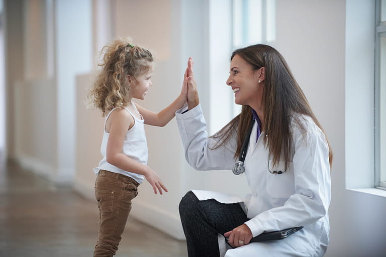 a physician and a young patient give each other a high five