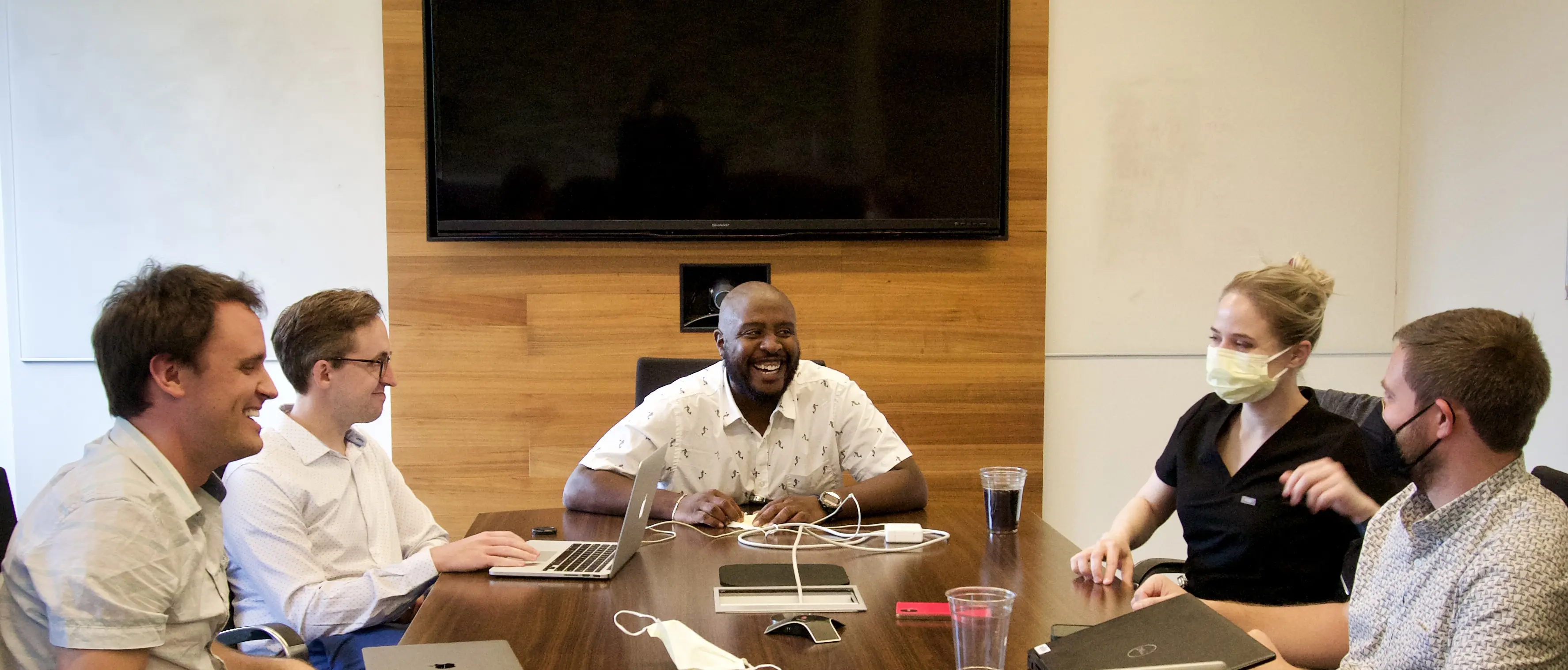 Five fellows discuss medical cases while seated around a table in a conference room