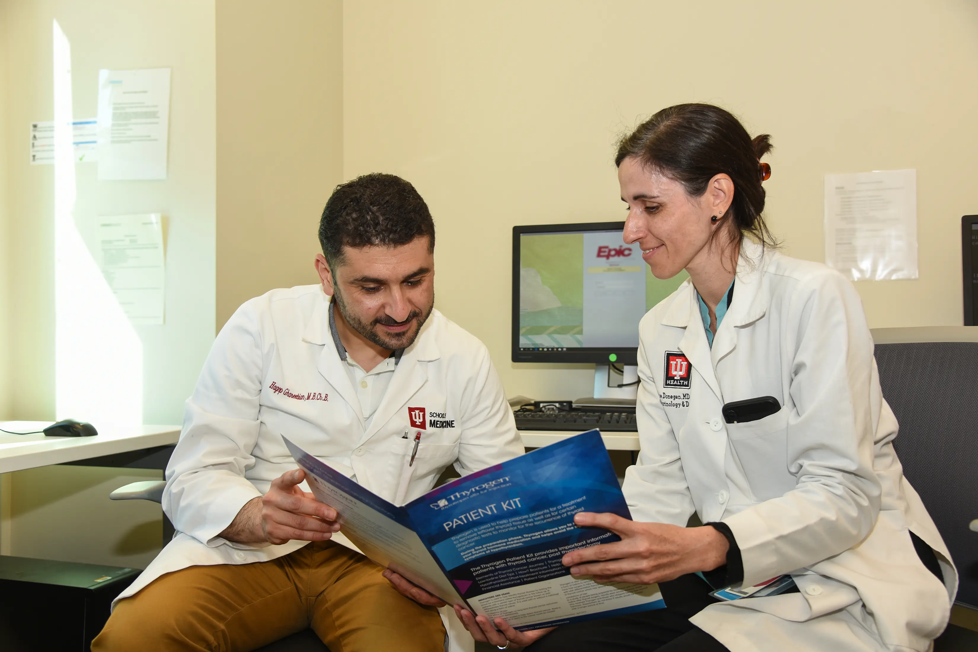 Two physicians in white coats look over a document together
