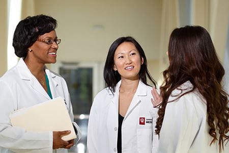 faculty members in white coats speaking with each other