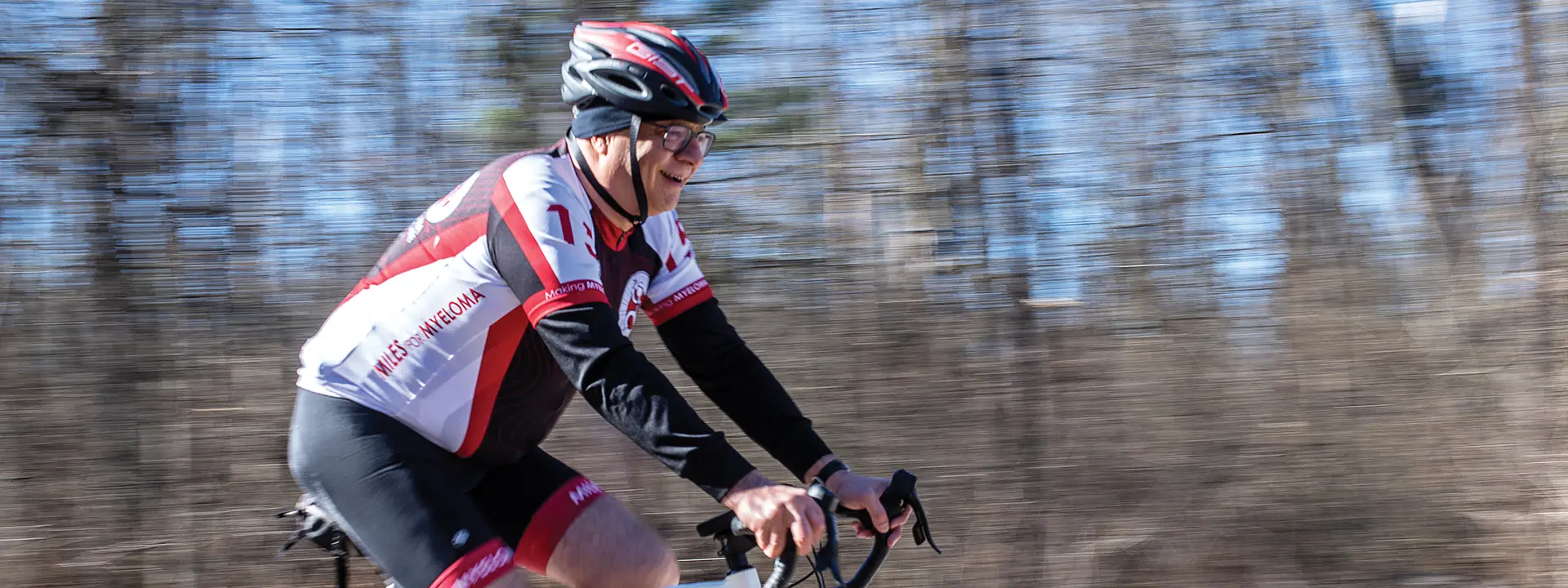 rafat abanour rides a bicycle with blurred trees in the background