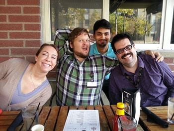 four people sitting at a table outside at a restaurant