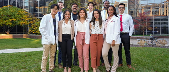a young group of diverse medical students pose outside