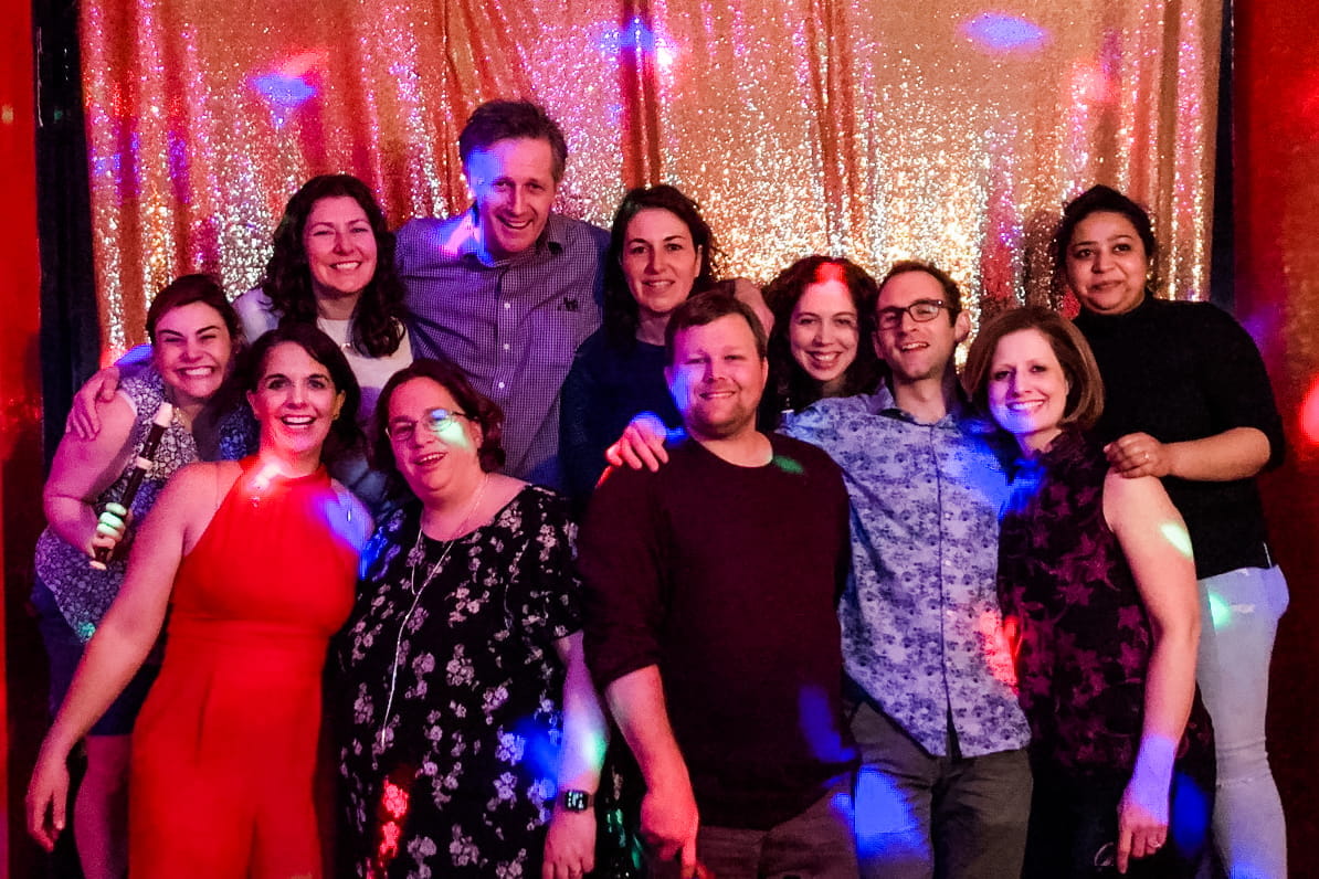A posed group photo of people smiling in a party room.