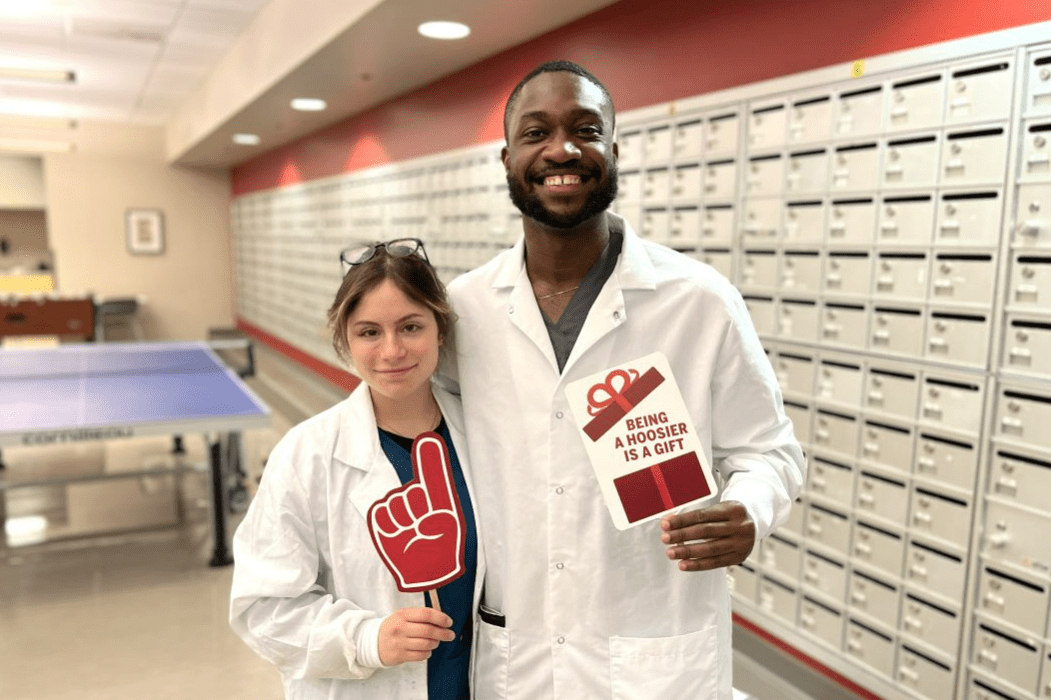 two students in white coats smiling