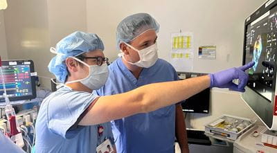 two physicians review patient vitals on a monitor