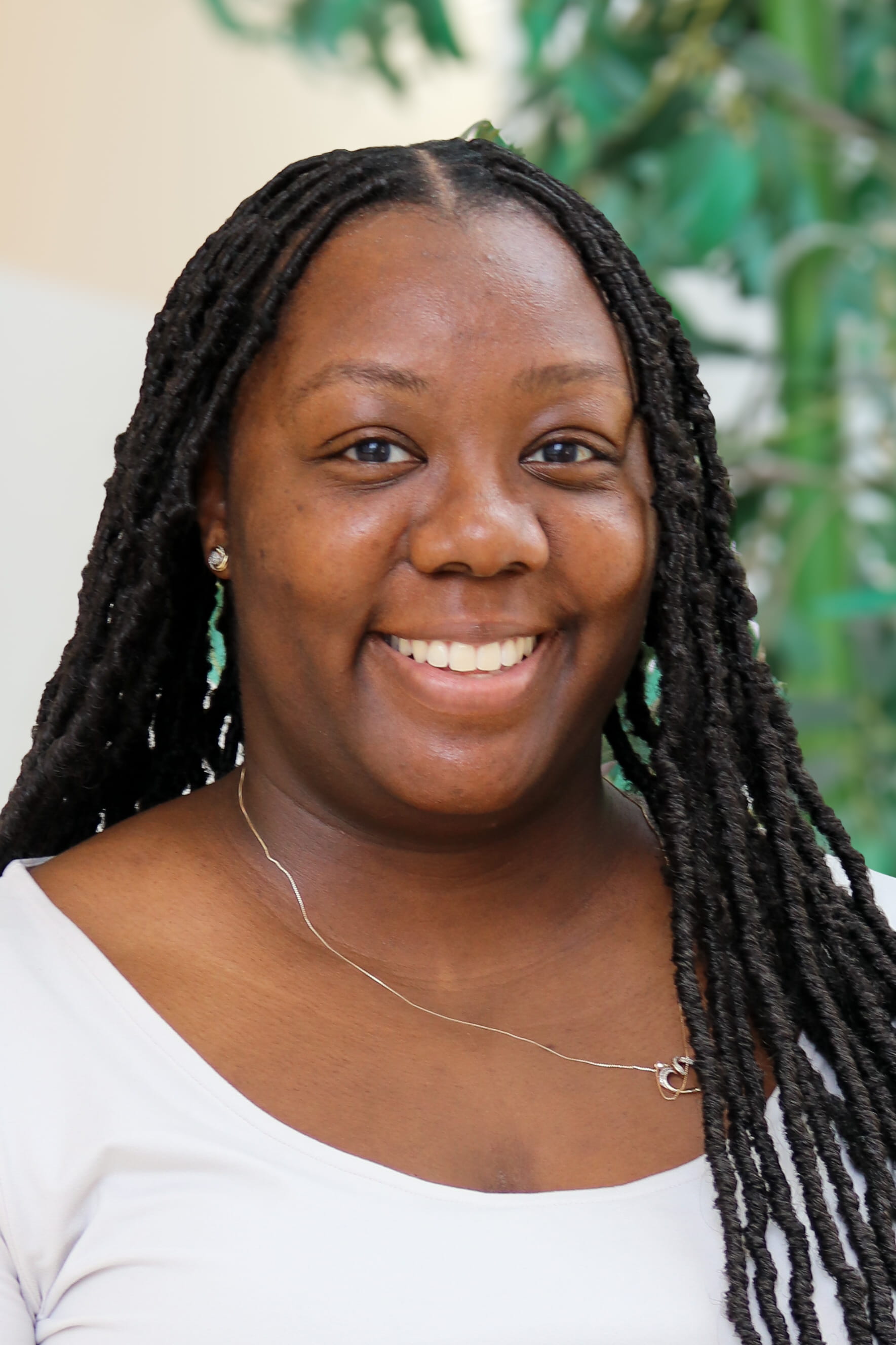 Faith Coleman smiles for her headshot wearing a white shirt and necklace.