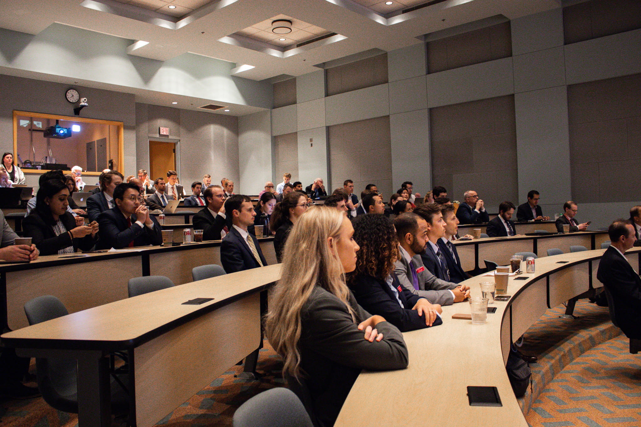 An auditorium is filled with attendees for an annual lecture. The audience faces an unseen speaker.