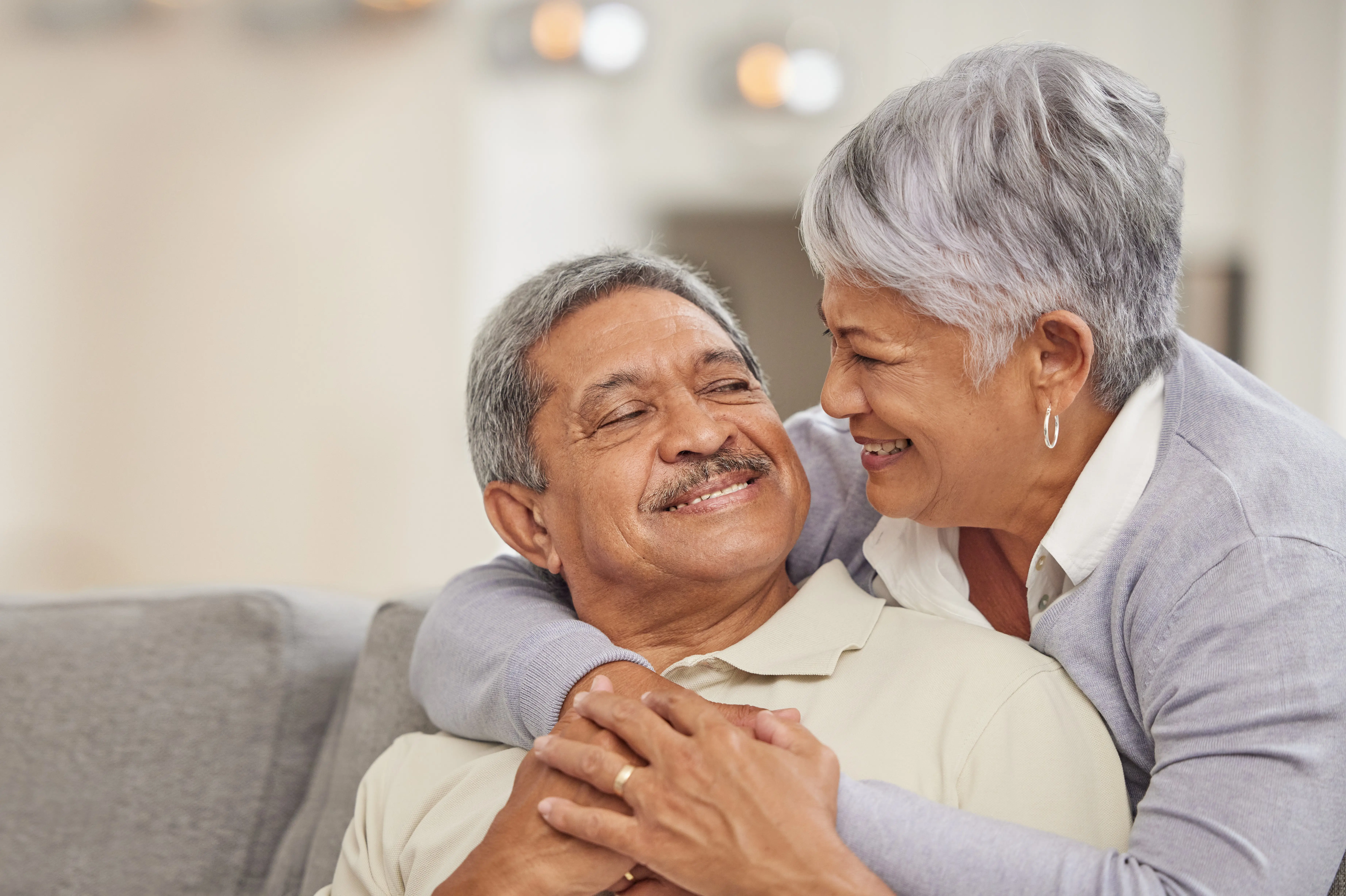 Hispanic older couple pictured with wife embracing husband around the shoulder. 