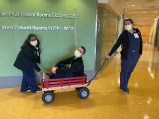 two fellows pull another fellow through riley hospital in a red wagon
