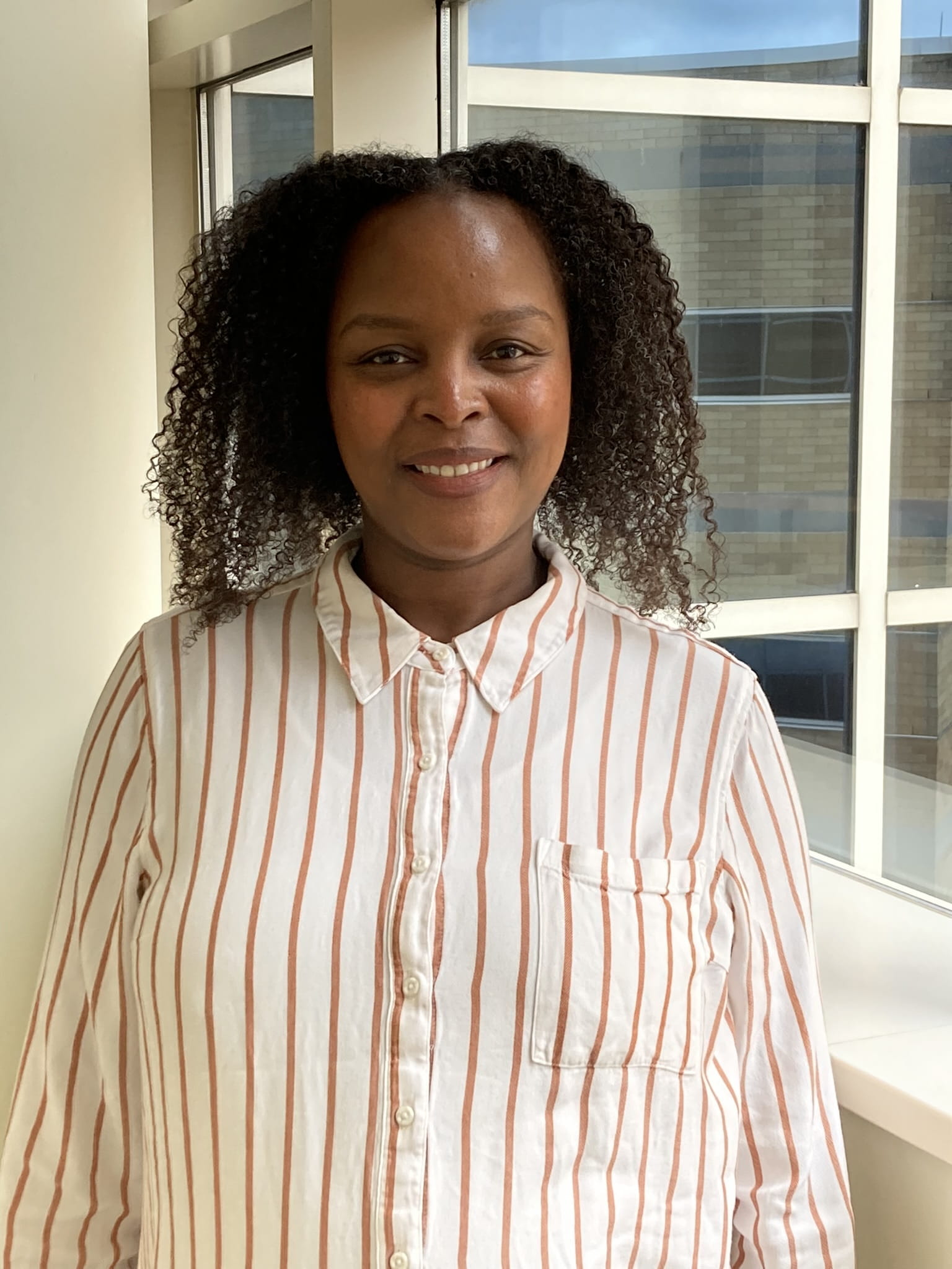 Staff Photo of Isabell Mwaura in a vertical shape with a window in the background.
