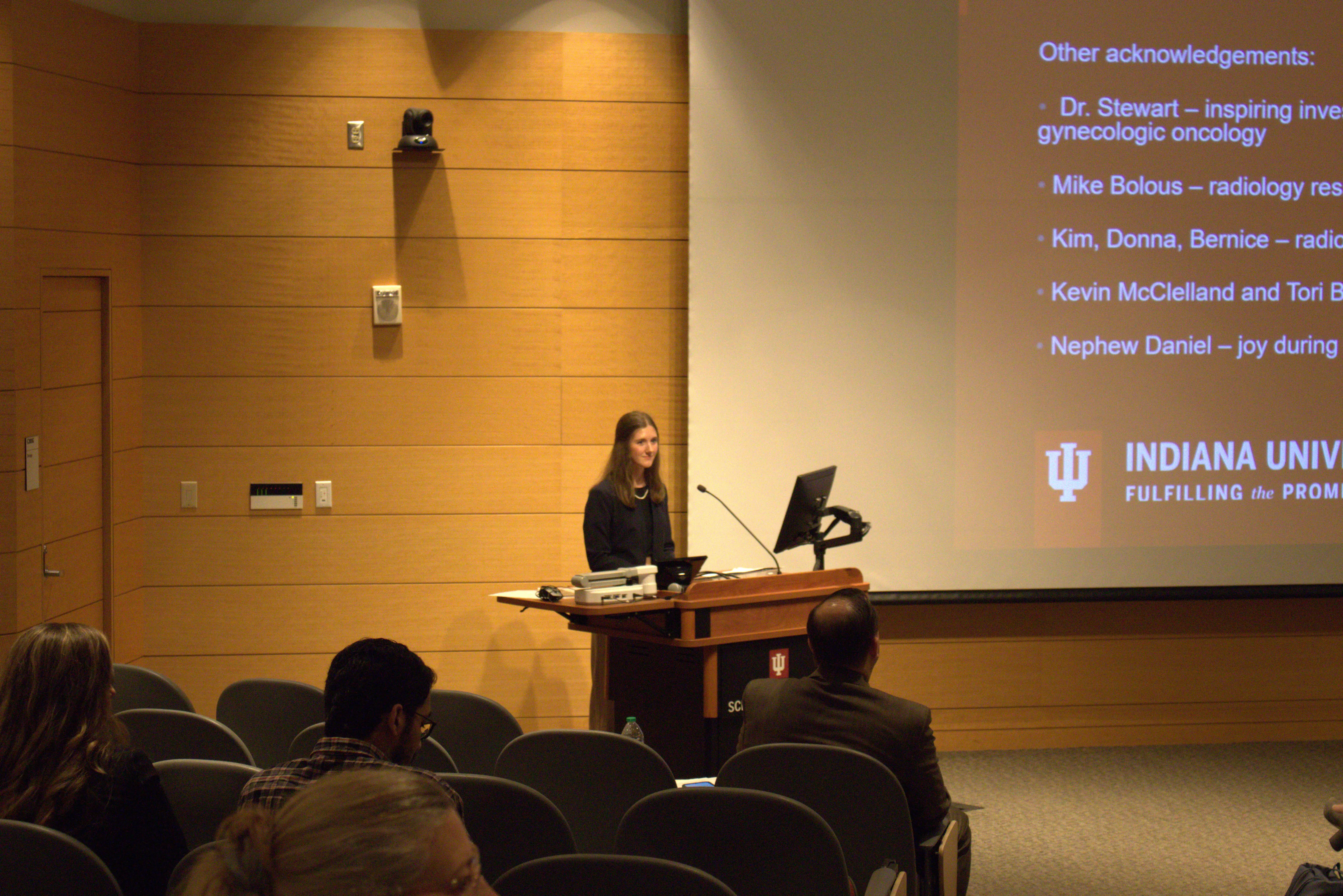 Dr. Shae Jansen stands at the lectern in front of her audience in the auditorium