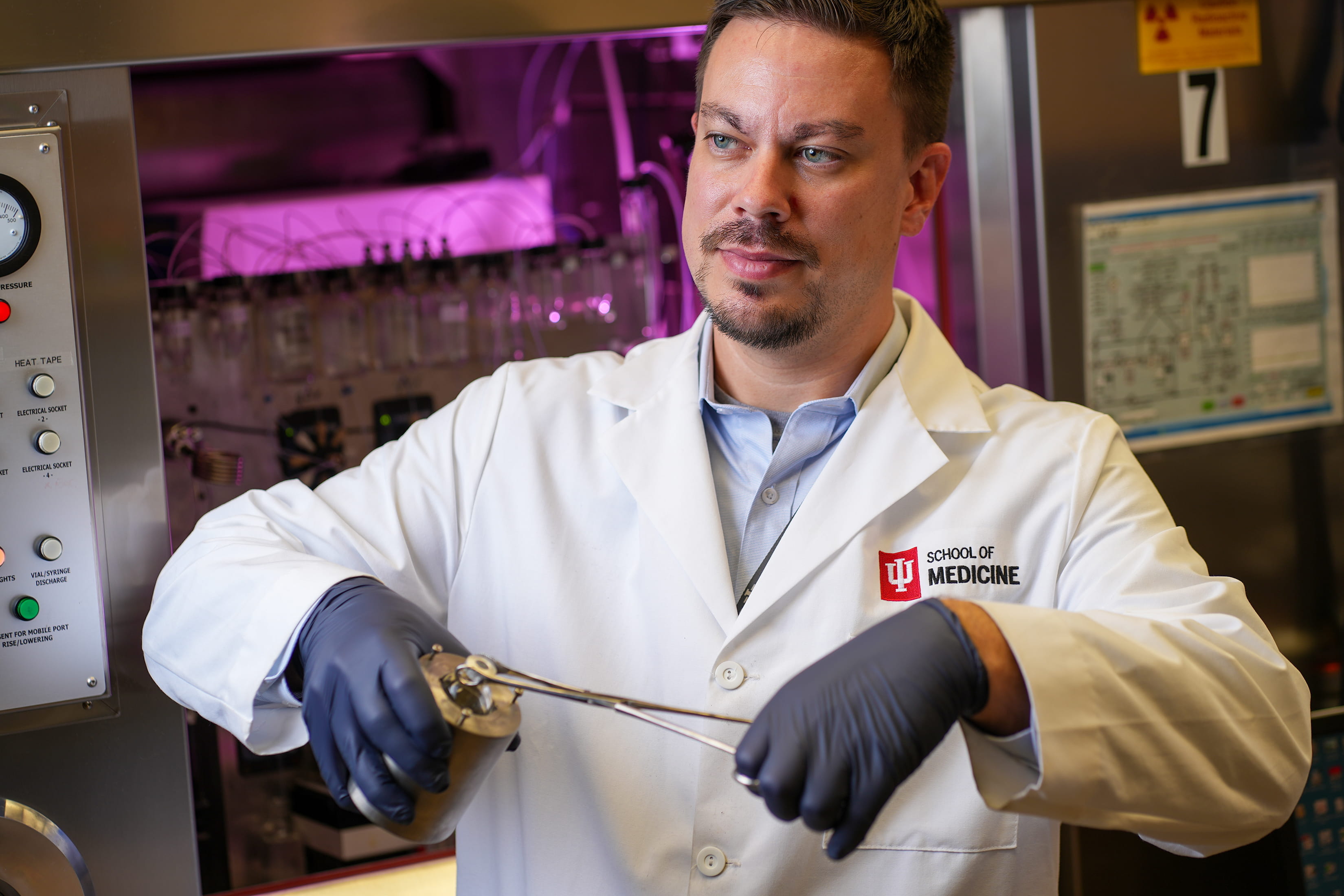 A female researcher manipulates robotic arms to move around materials.