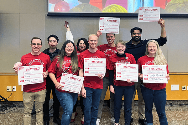 MSTP students pose for a photo with signs revealing their residency matches.