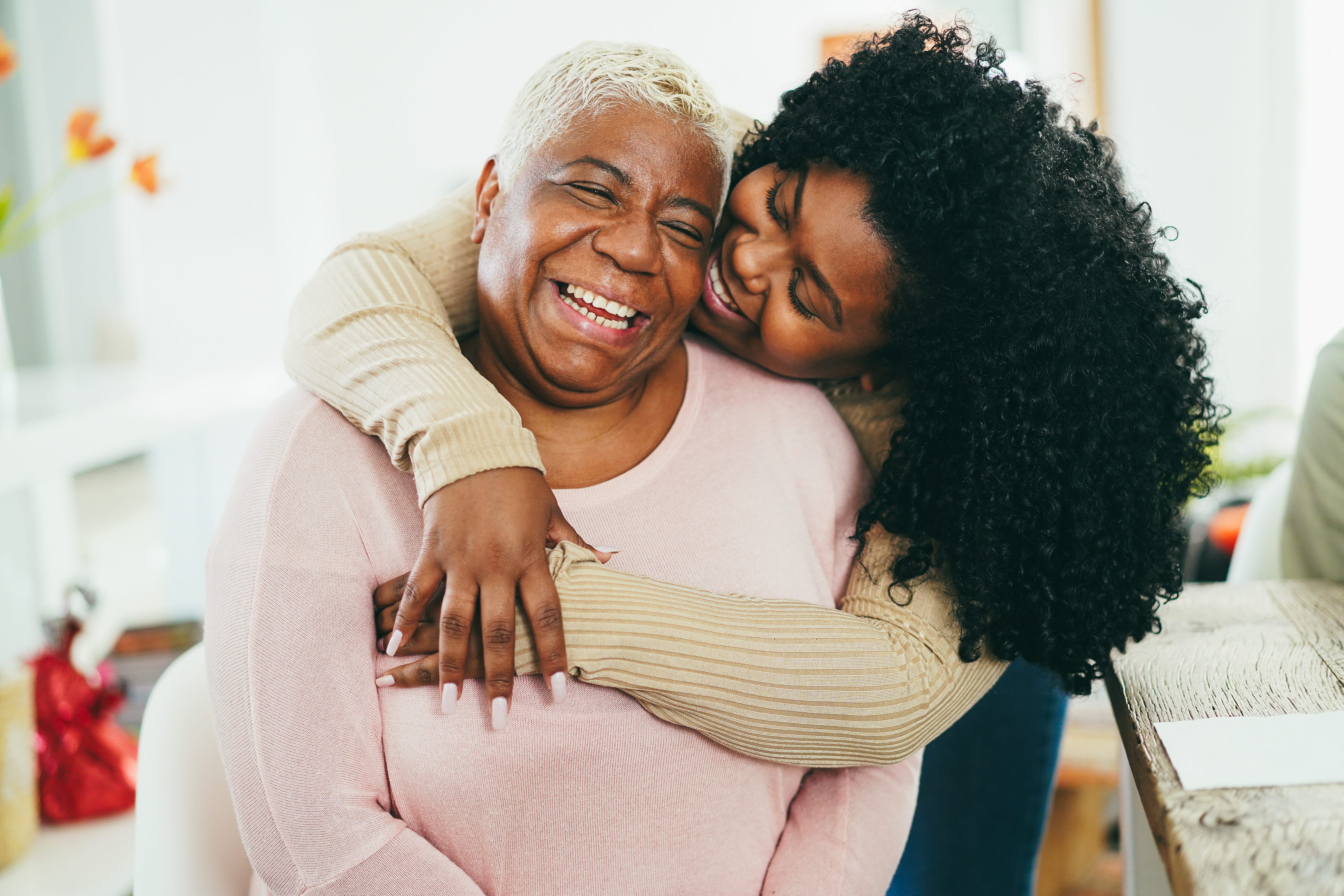 Older African American woman is embraced by her daughter over the shoulders.