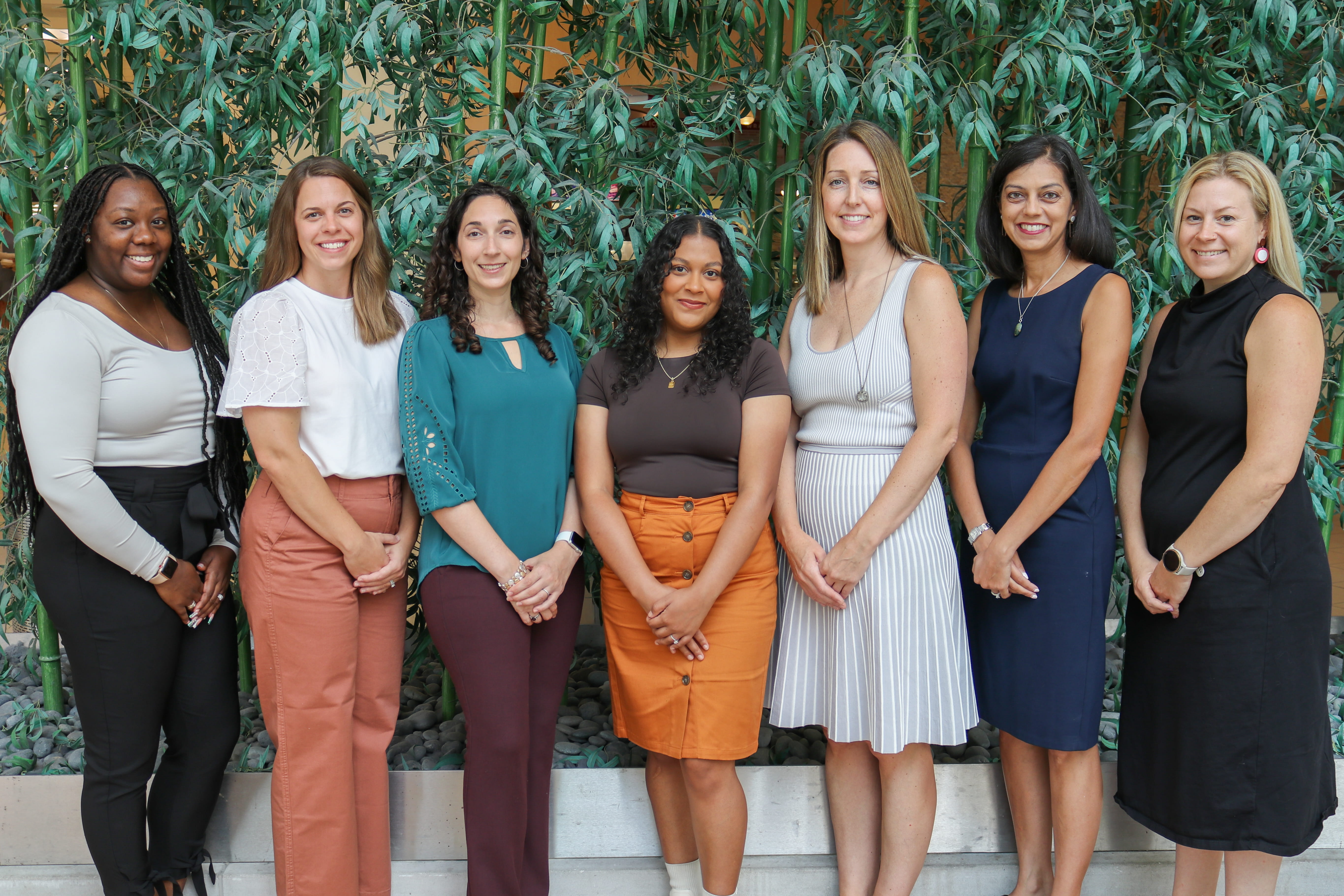 Team members stand in a straight line with a bamboo backdrop.