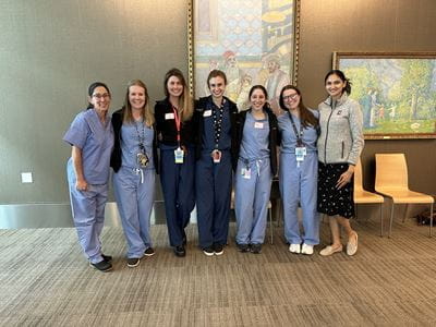 7 women from the orthopaedic surgery department stand together in their scrubs at the Perry Initiative event