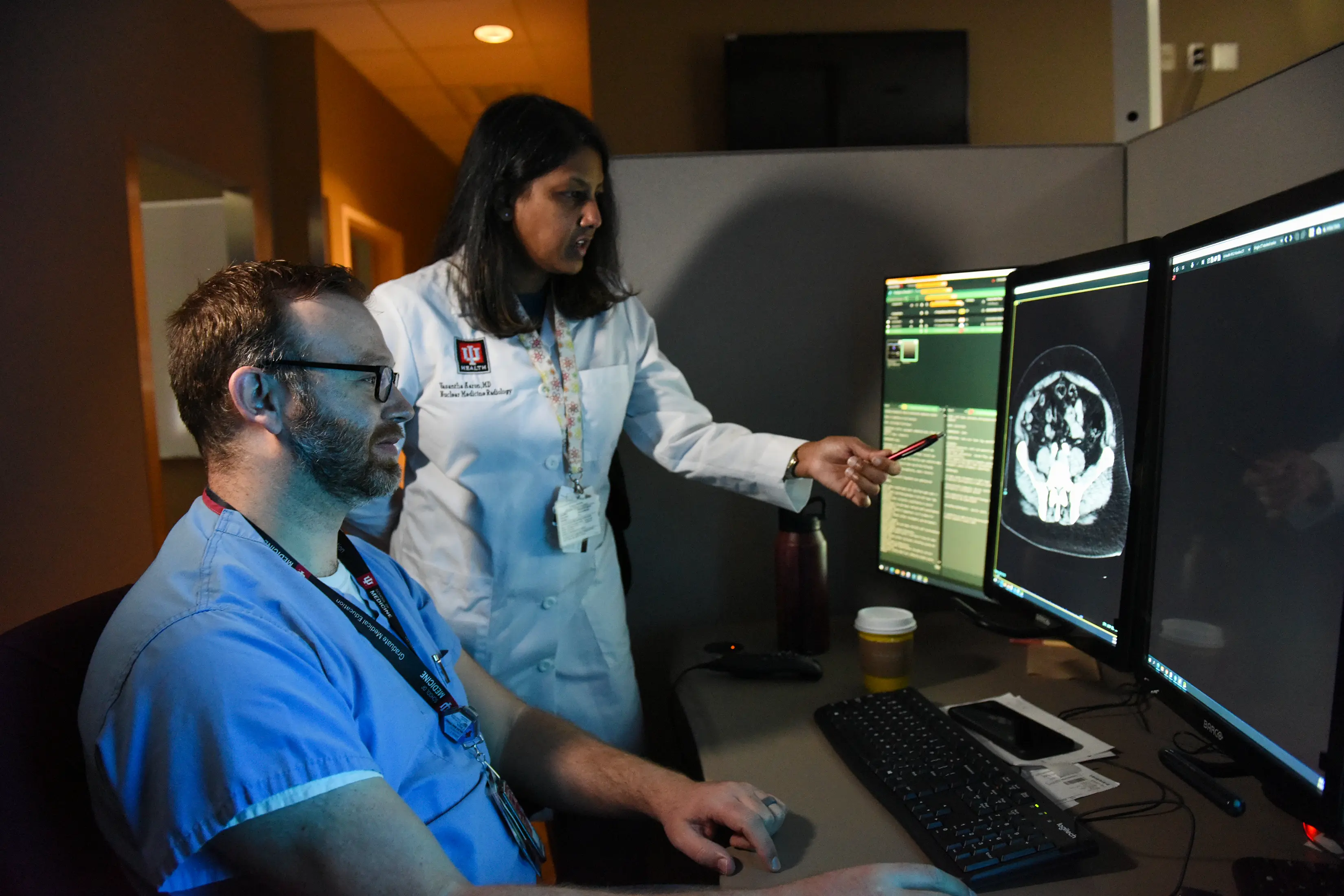 Image of female radiologist pointing to an abdominal scan while a male trainee observes.