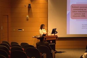 Dr. Allison Polidori stands at the lectern facing the audience in the auditorium