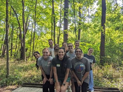 Residents stand crouched in two lines for their photo, with trees and nature behind them.