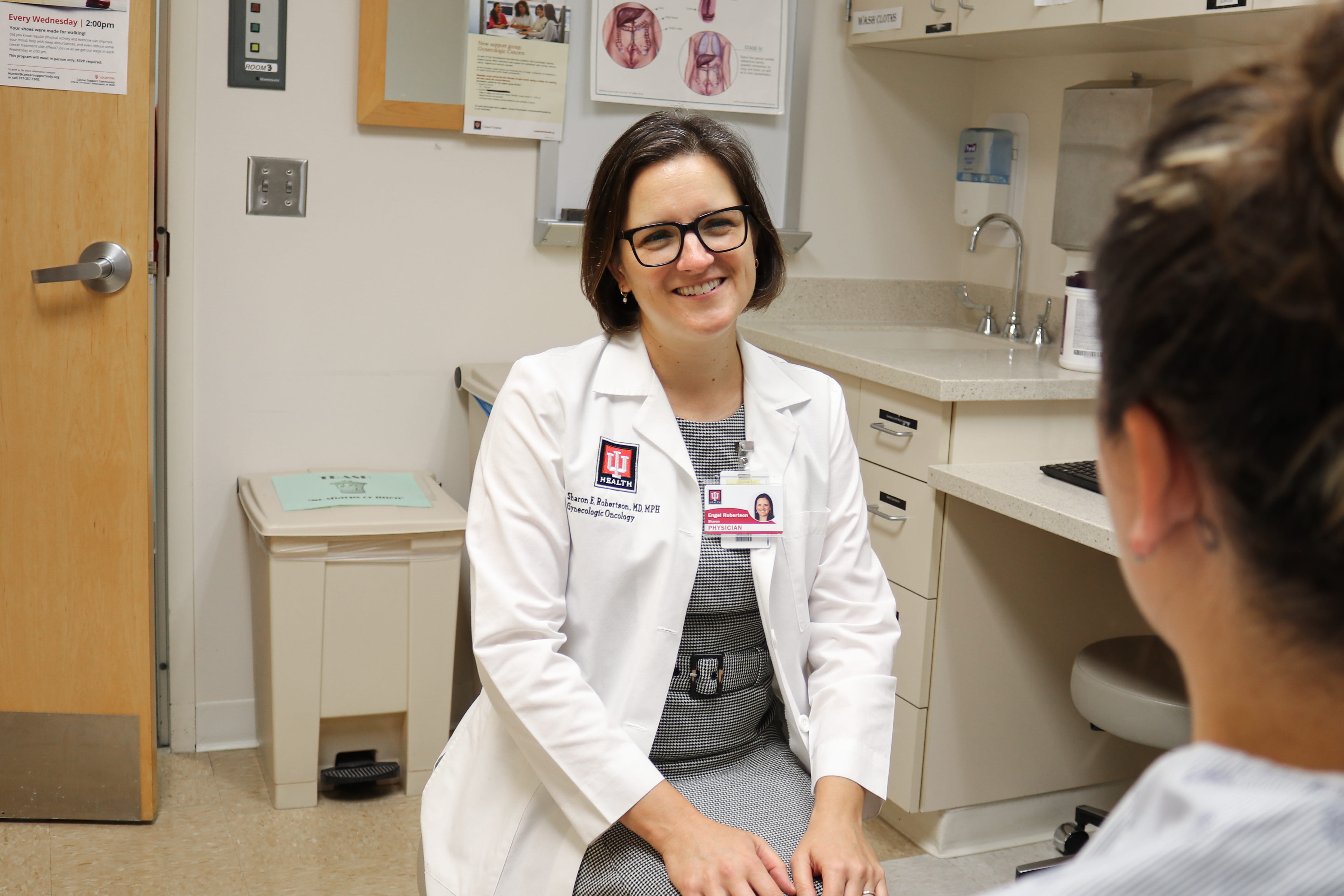 Sharon Robertson, MD, faces her patient, whose face is obscured, while sitting in the clinic