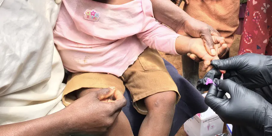 Malaria researchers administer a blood test to a small child. 