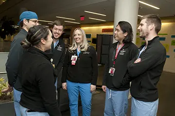 Six residents smile and speak together in a hallway