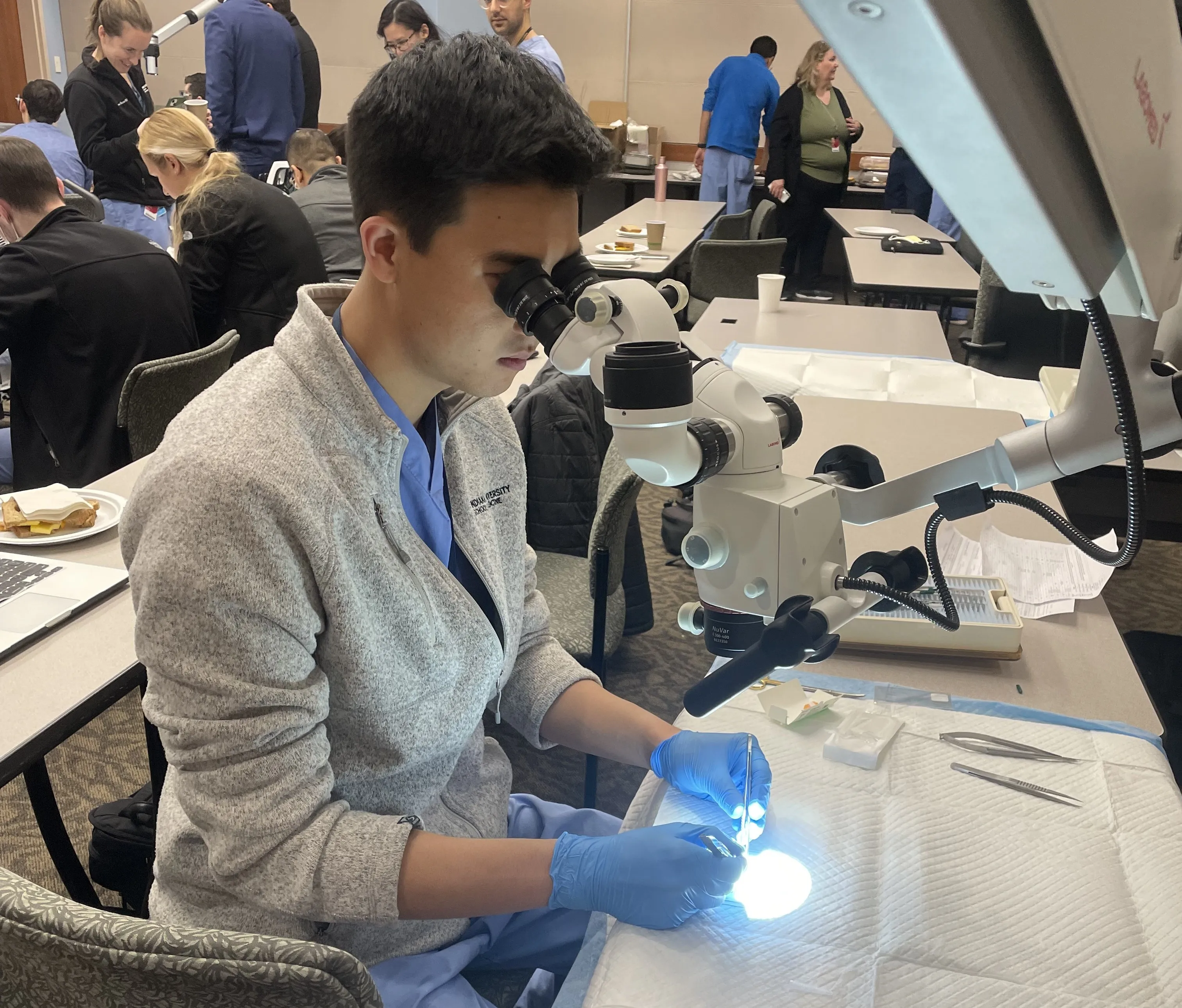 Urology trainee practices a microsurgical technique using a surgical microscope.