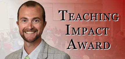 Dr. Zach Weber smiling in front of Teaching Impact Award banner recognizing excellence in medical student education and interprofessional collaboration.