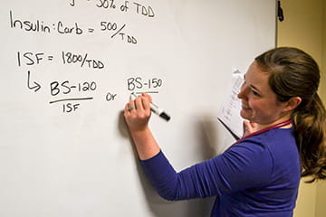 Faculty member uses white board for lesson.