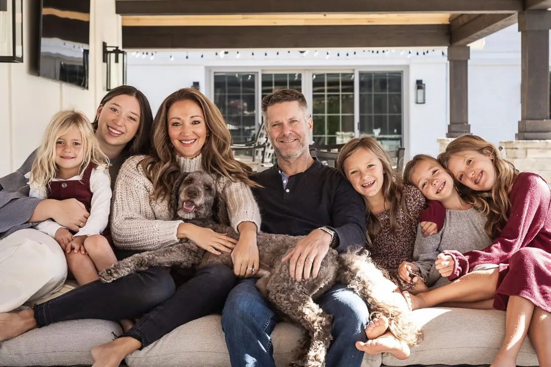 Lindsay Weaver and her husband sit in the center of a large couch, surrounded by their five children and family dog.
