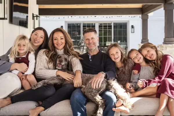 Lindsay Weaver and her husband sit in the center of a large couch, surrounded by their five children and family dog.