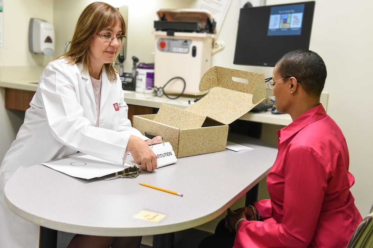 liana apostolova sits across a table from a woman who is a participant in the LEADS study. Apostolova holds a flash card for the woman to read.