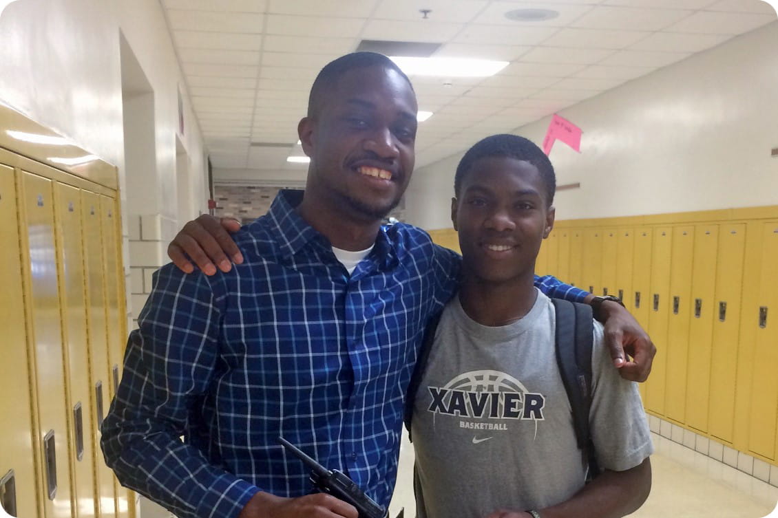 myke spencer and a student stand with their arms around each other in a school hallway