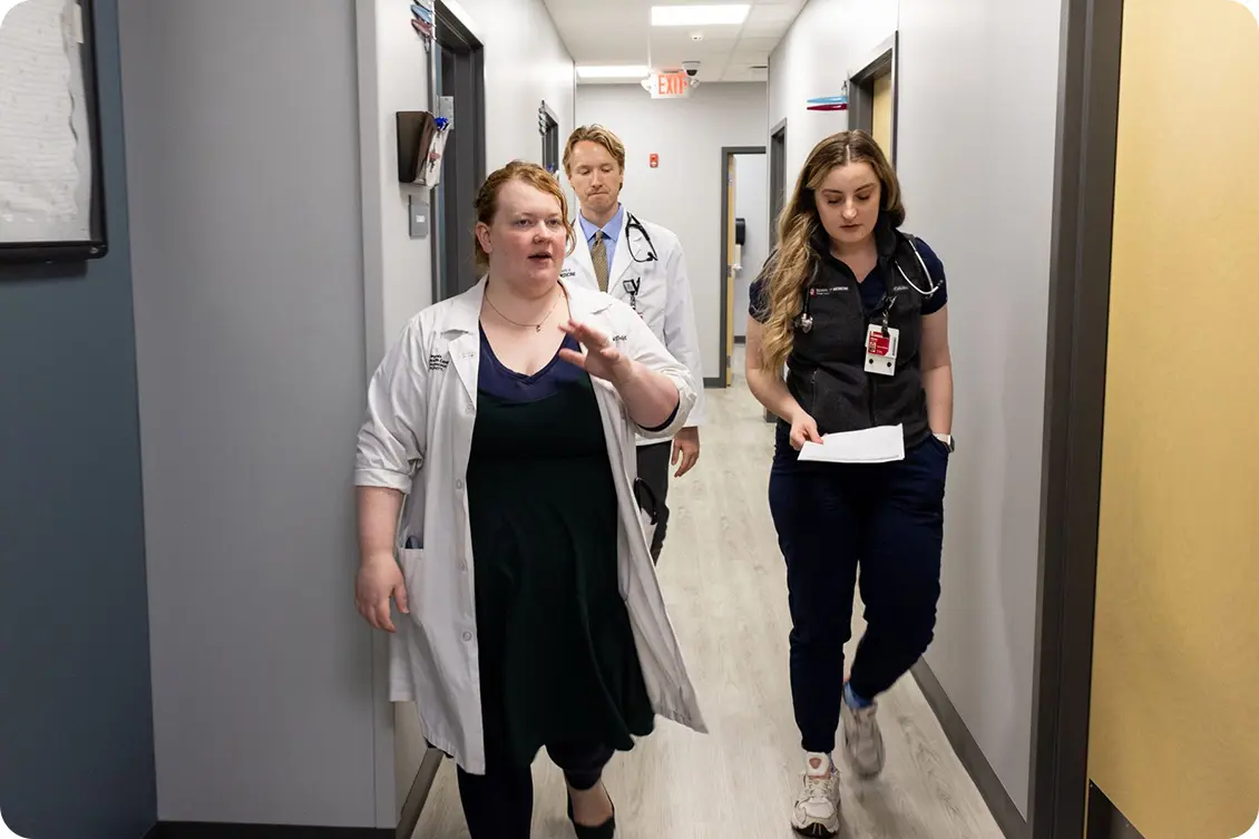 Angela Hatfield and students Andrew Gauger and Maddie Wright walk down the hallway of a medical clinic