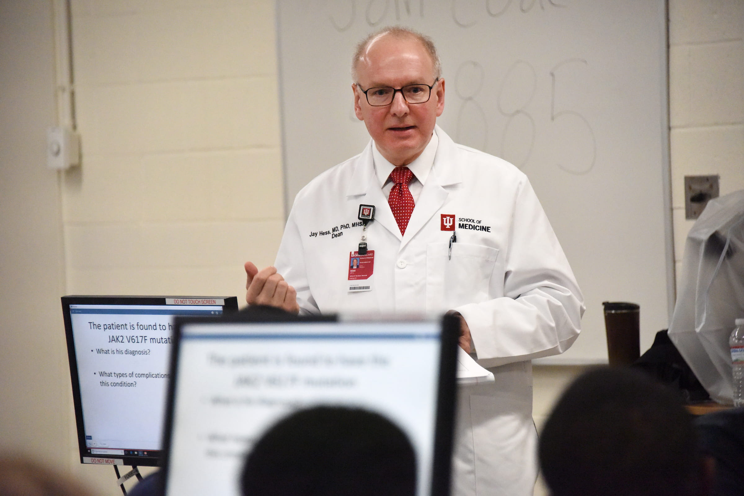 Dean Jay Hess wearing coat talking to classroom