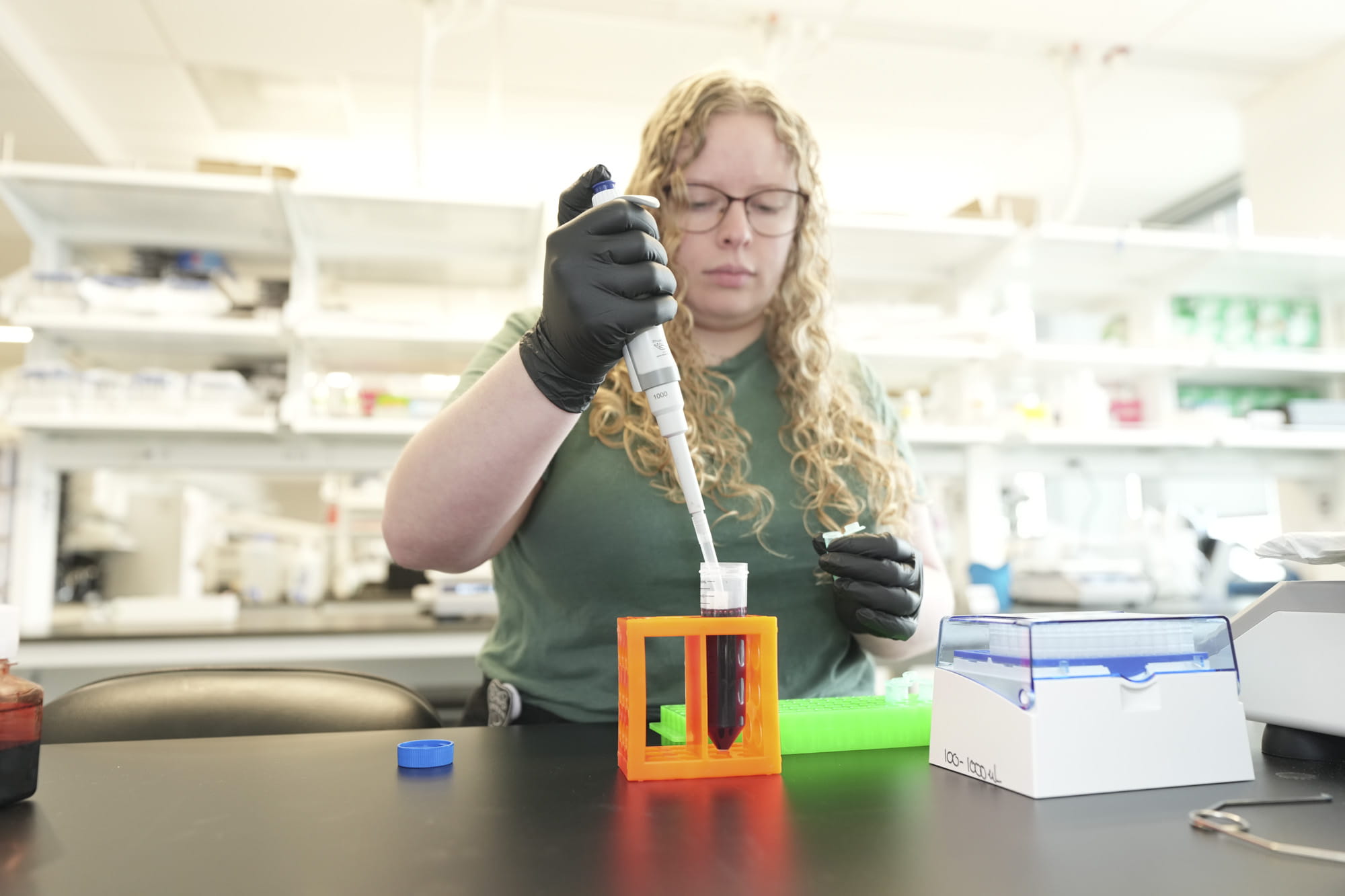 A researcher holding a syringe and inserting in test tube in a lab setting. 