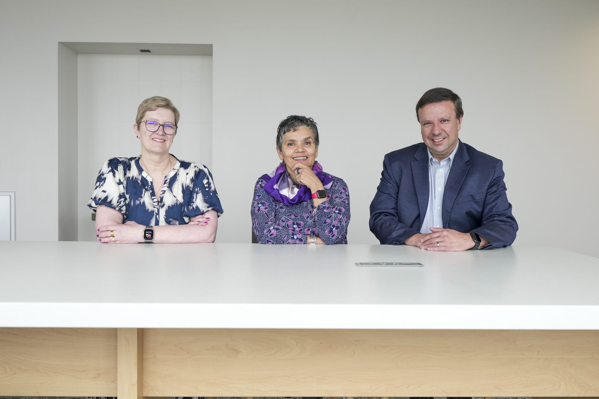 Donna Wilcock, Malu Tansey and Jason Meyer sit together at a long white table